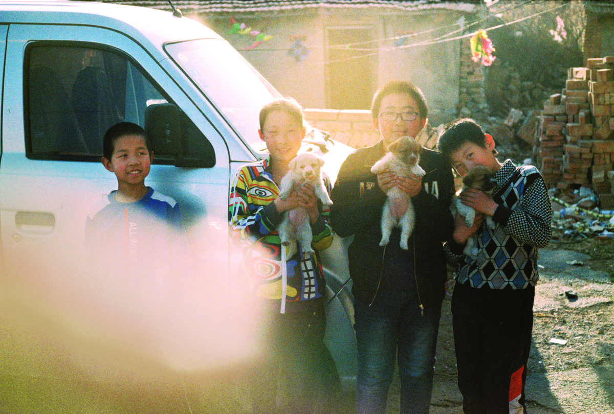 Kids from a village on the Hebei/Inner Mongolia border proudly show off their pet puppies