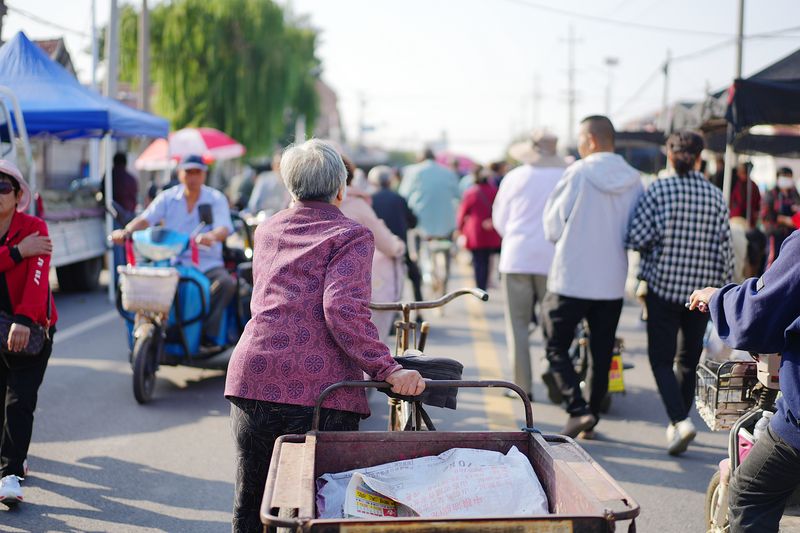 Older woman pushes her electric cart in Laizhou to gather at the local market