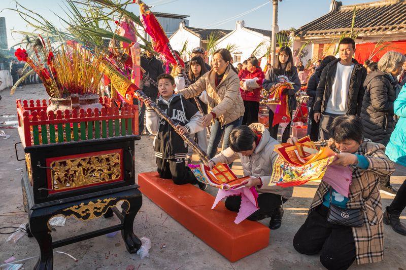 Villagers pay respect to the Heavenly Lord by offering paper money, incense, and a feast