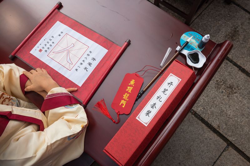 First Writing Ceremony typically requires a Chinese writing brush, paper, ink, and a pendant featuring an auspicious phrase.