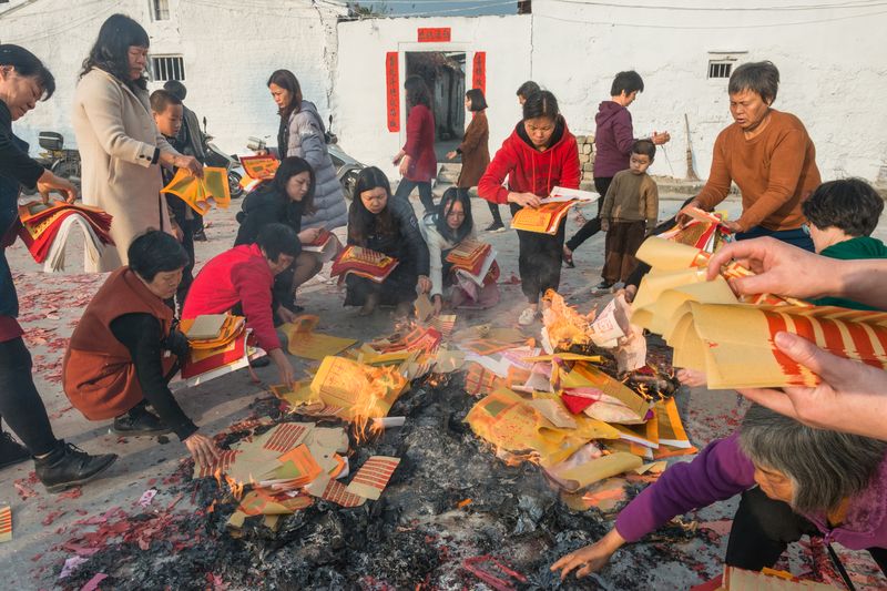 Villagers burn paper money in the fire to pray for a prosperous New Year