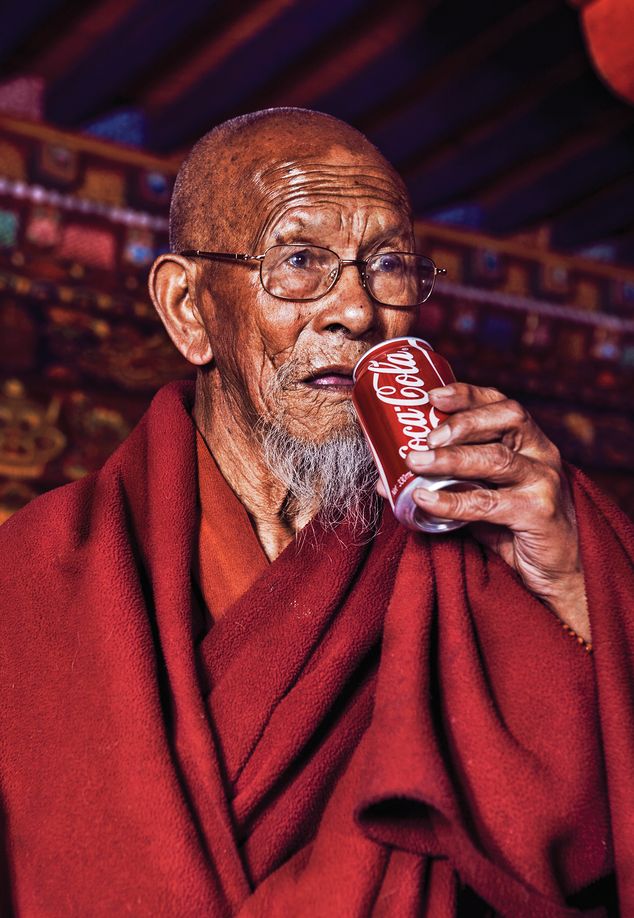 A monk drinks a Coca Cola in “Modernizing the World Roof,” 2014