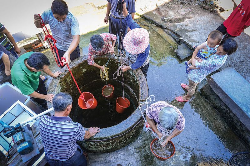 Villagers work together to drain the well, bucket by bucket