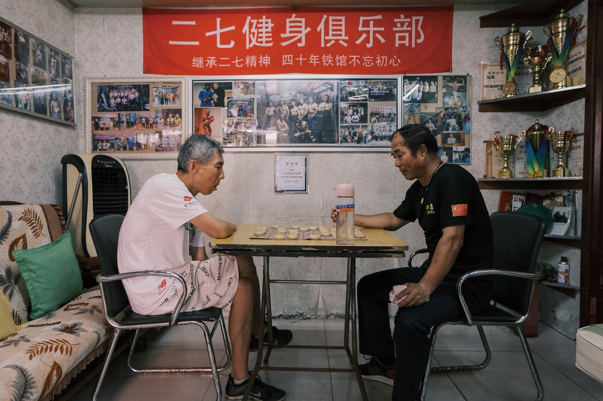 Feng Jingchang (left), 60, plays Chinese chess with Mi Wenyuan during a break. Photos of members and trophies they’ve won are displayed in the gym.