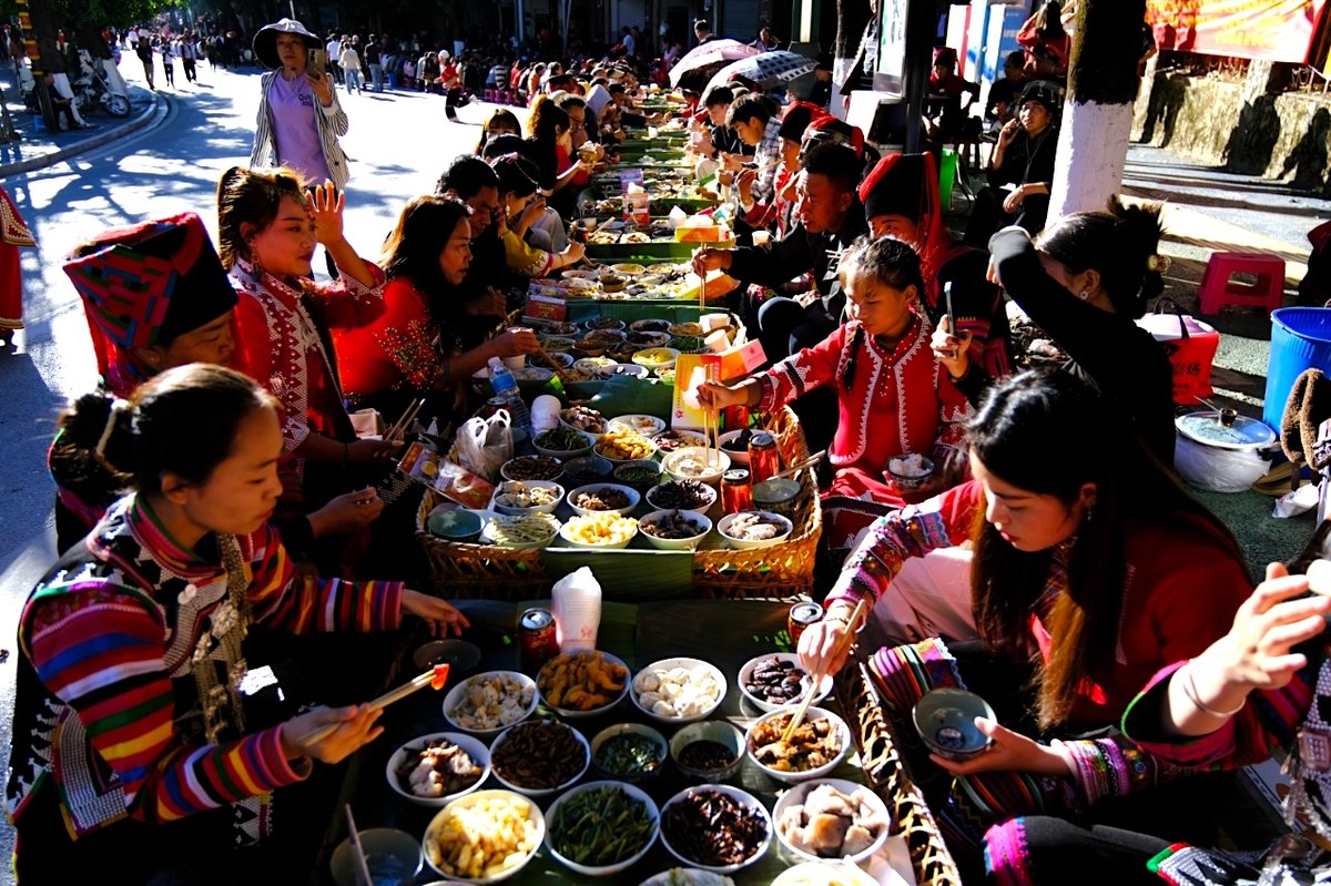 Tourists and locals celebrate feast together and experience a variety of Hani minority style dishes during 2024's Long Street Banquet