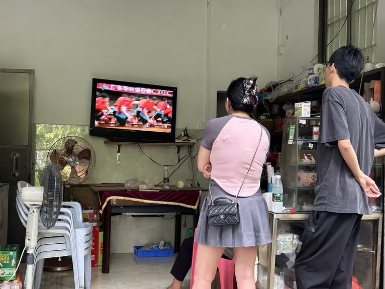 Locals watch a livestream of the race on TV
