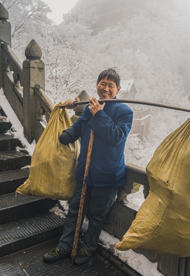 porter transporting luggage up Wudang Mountains, China