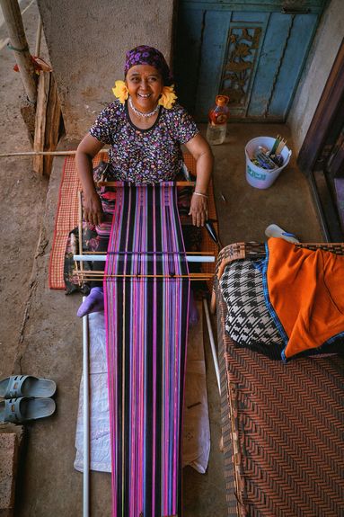 A Va woman hand-weaves a purple brocade