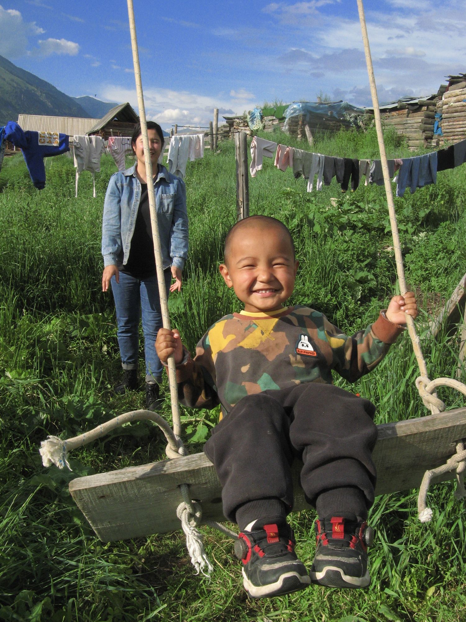 A Kazak child enjoys swinging on a handmade swing near his home at Altay