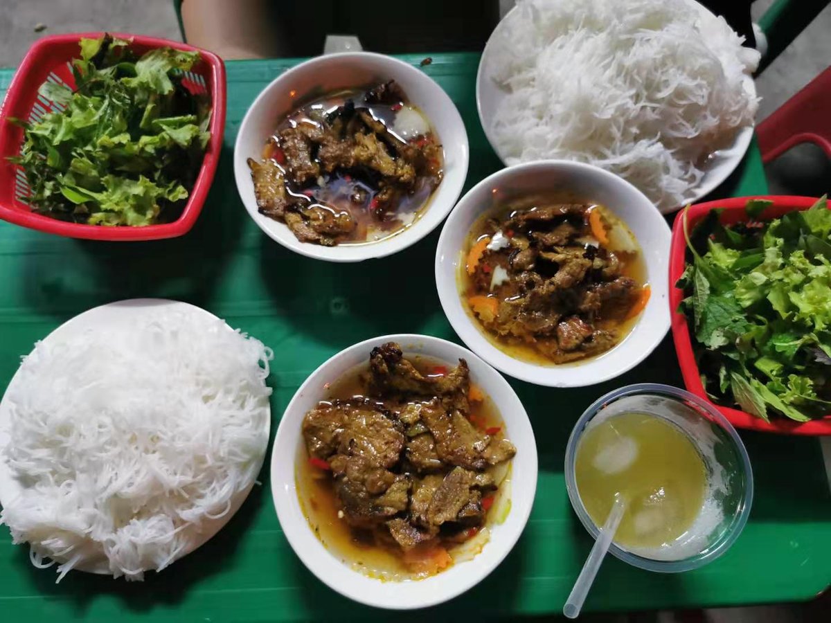 A dinner table in Vietnam including bún chả, a typical Hanoi dish made of grilled pork, rice vermicelli, and fresh herbs