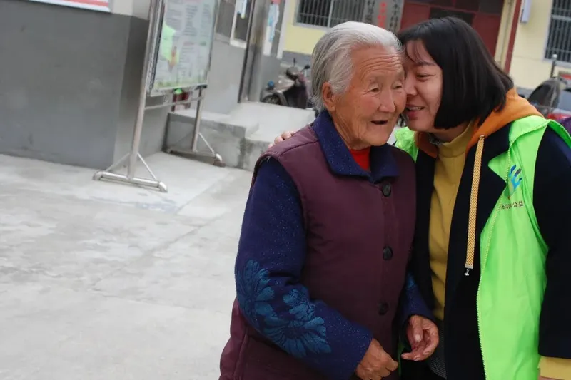 Volunteer hugging a Chinese granny as she takes her portrait