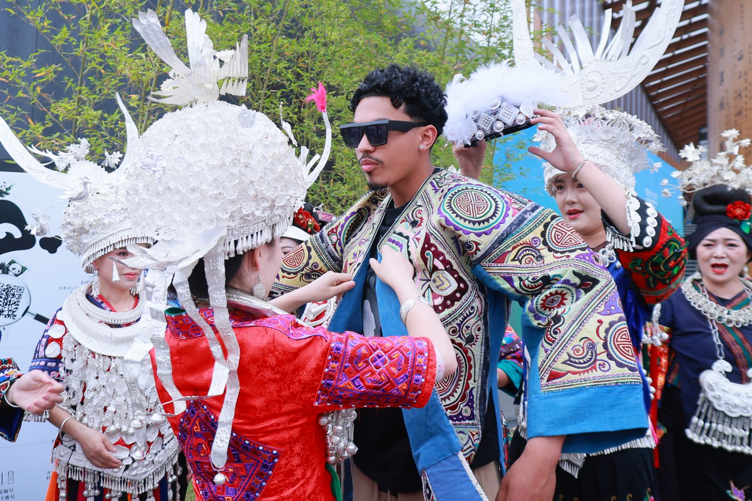 Villagers from Kaili at this year’s World Expo help interested audience to dress traditional Miao ethnic costumes