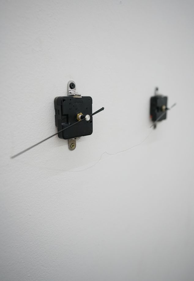 “Each Other,” an installation that connects the hands of two clocks with one thin hai