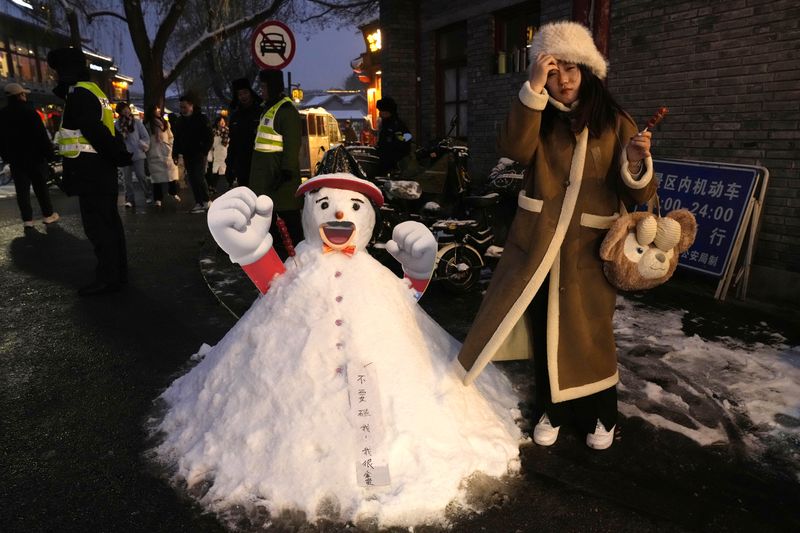 A woman smiling beside a snowman in Beijing
