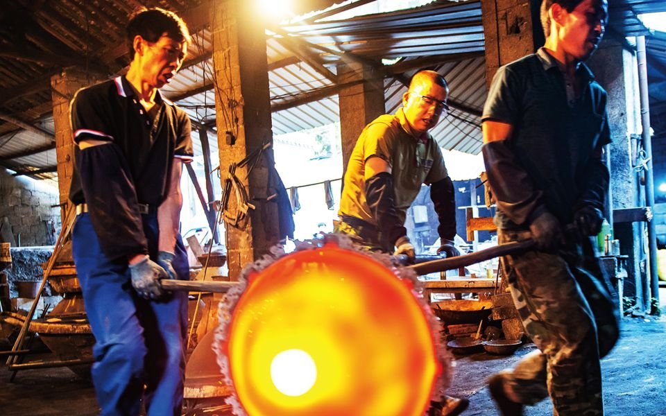 Factory employee's transfer a newly formed Chinese wok to a new location.