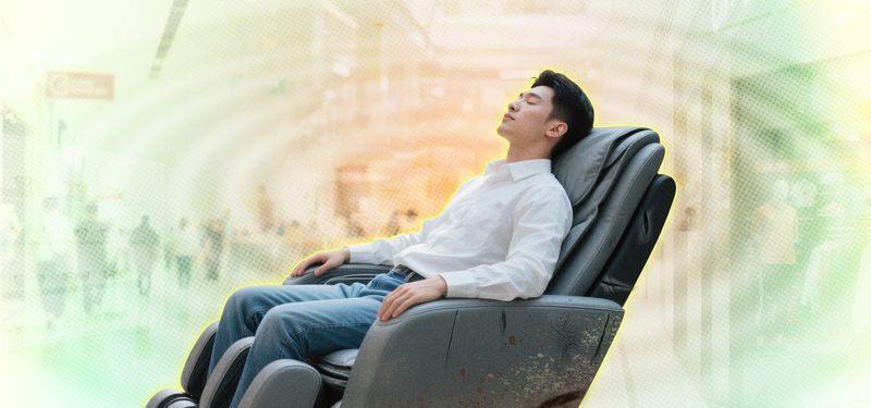 Chinese man sitting, relaxing in a public vending massage chair