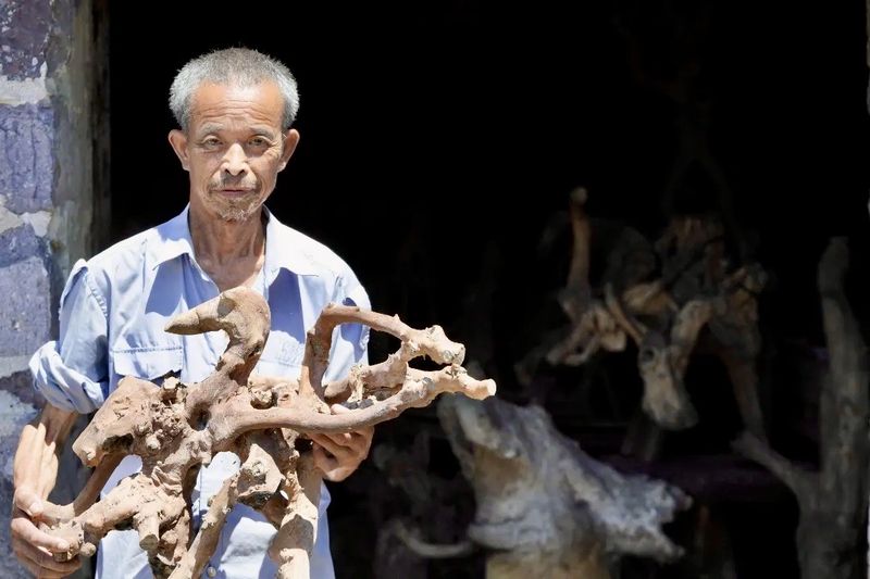 Elderly man holding a carved root