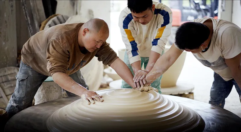 Three men work on a supersized porcelain piece, one of many types found in the "Porcelain Capital of the World"