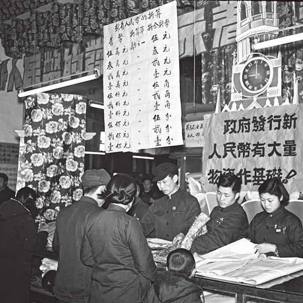 Chinese customers using renminbi notes to exchange for rolls of cloth at a shop in Beijing. 