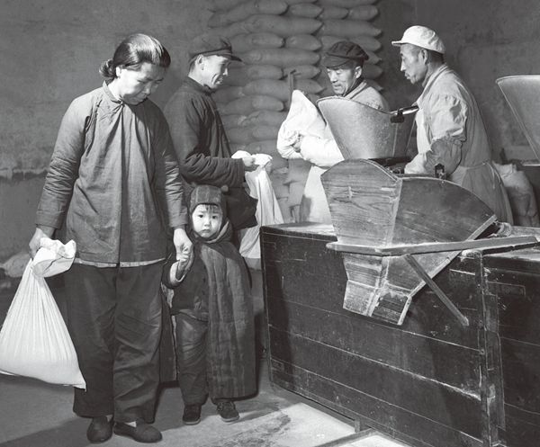 An older Tianjin women holding a child&#x27;s hand after she used coupons to buy a bag of rice. 