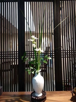 Chinese flower arrangement in tall white flower vase