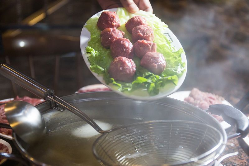 Beef balls being dropped into a hotpot