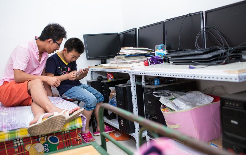 Chinese father and his son playing a video game together