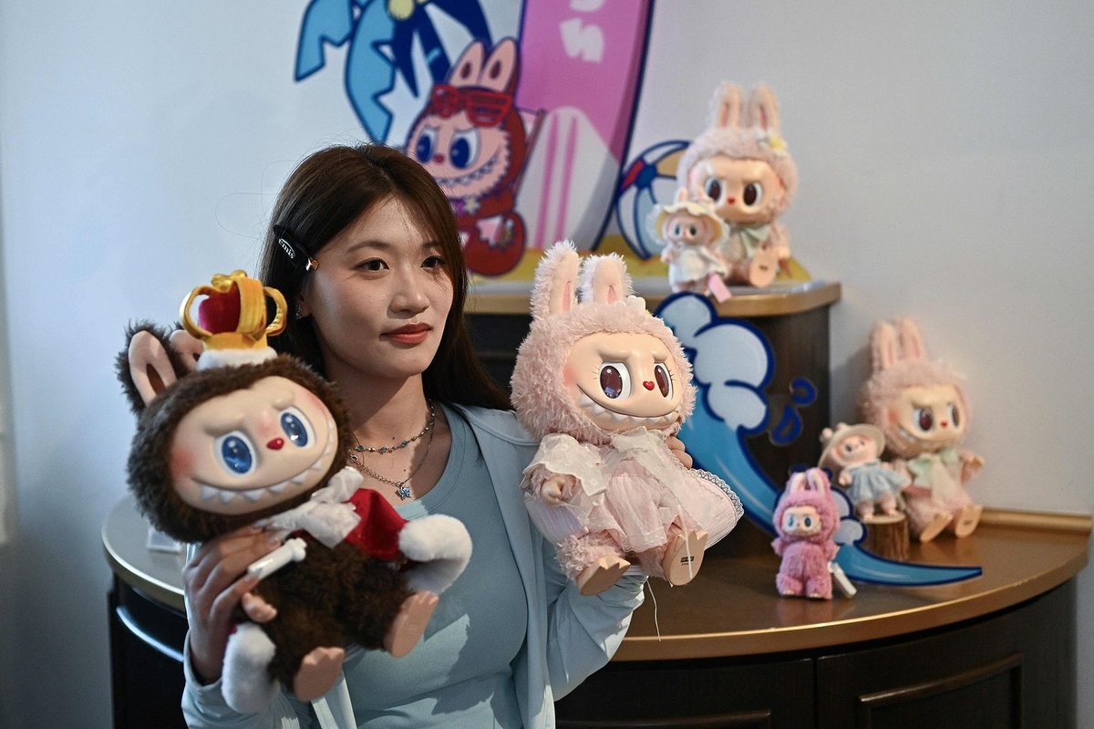 A visitor poses with Labubu dolls at the store in Pop Mart’s theme park, Popland, China adults emotional economy