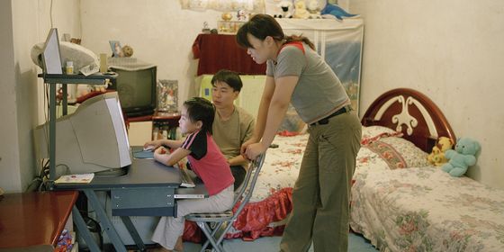 Chinese parents watching kid play computer game in Beijing_VCG31N594770664