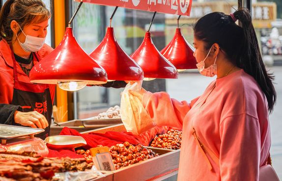 Chinese woman buying chestnuts at a stall in Wuhan