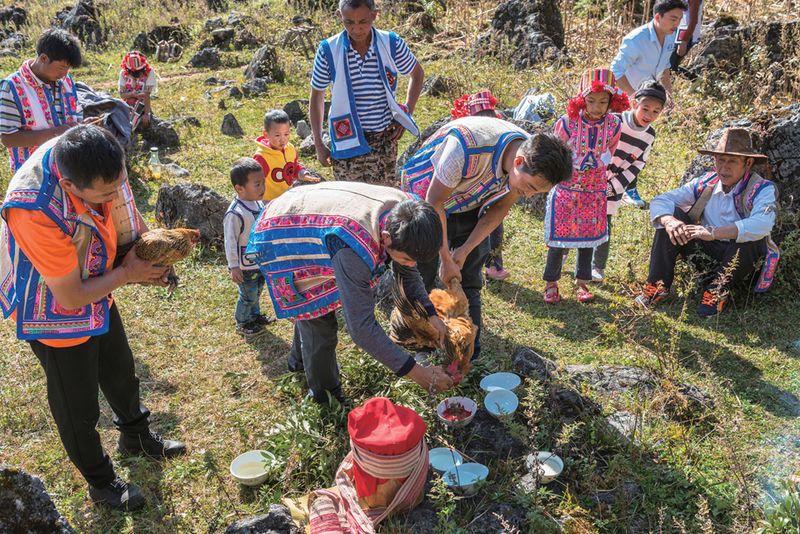 The Bo clan head prepares the altar by sprinkling chicken blood and alcohol on the ground