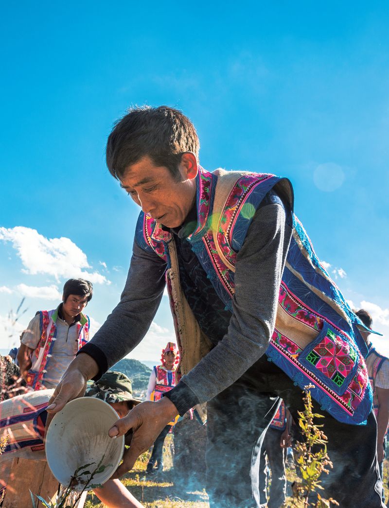 A man from the Bo ethnic minority pours offerings onto the ground