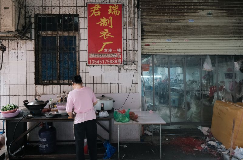 A woman dices vegetables in front of a garment factory in Lujiang village, Guangzhou, June 10, 2023.