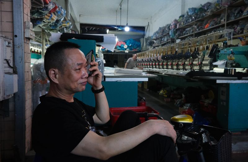 Zhou, a garment worker who just turned 60 years old this year, sits on an electric scooter in the front of a garment factory in Lujiang village