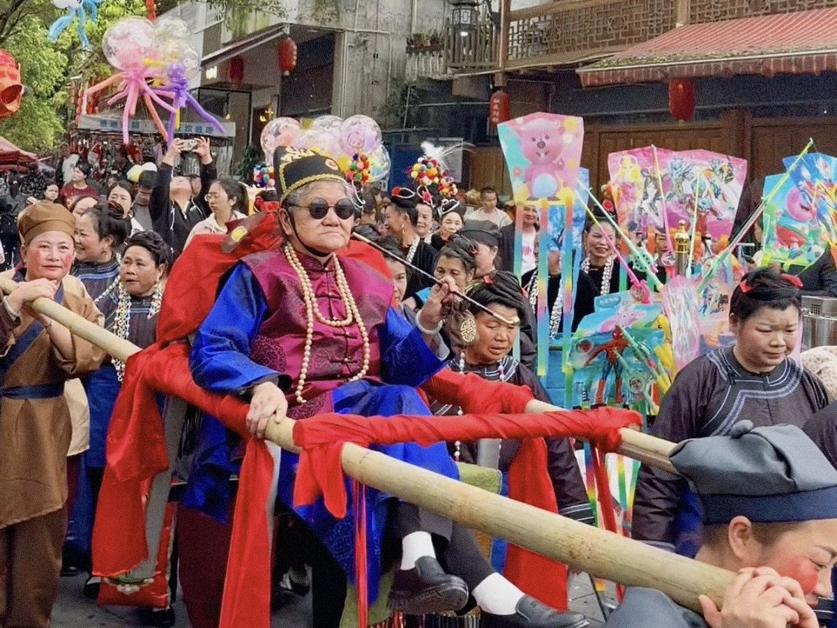 Women dressed in straw skirts and red turbans parade with straw dragons and fish lanterns, praying for favorable weather and a bountiful harvest, while men in the outer ring of the ceremonial processi