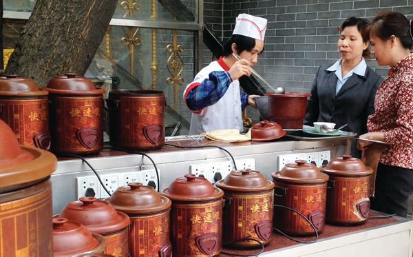 A cook serves medicinal soup to Chinese customers at a Cantonese restaurant. 