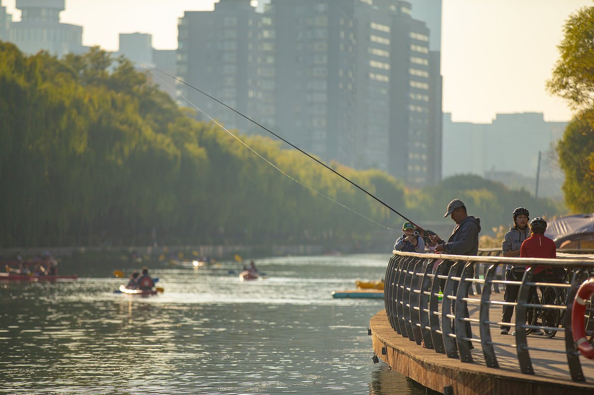A fisherman peacefully fishes during the day at Liangma River in Beijing