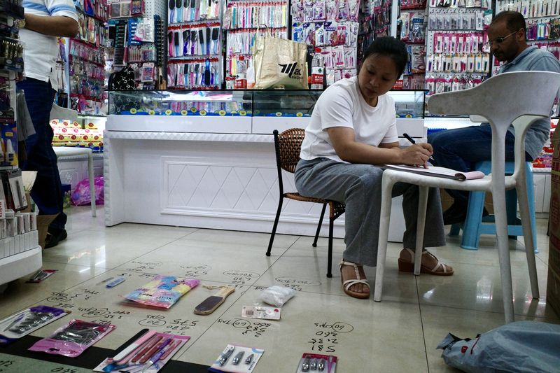 A shop owner doing calculations on their inventory of household products