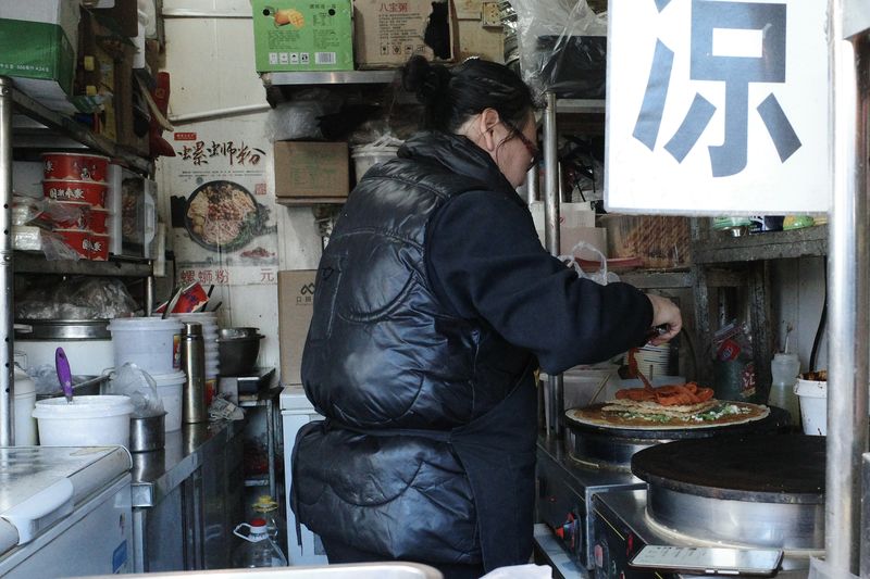 Yang Hua busy preparing a latiao order for her customer in Beijing's Changping District