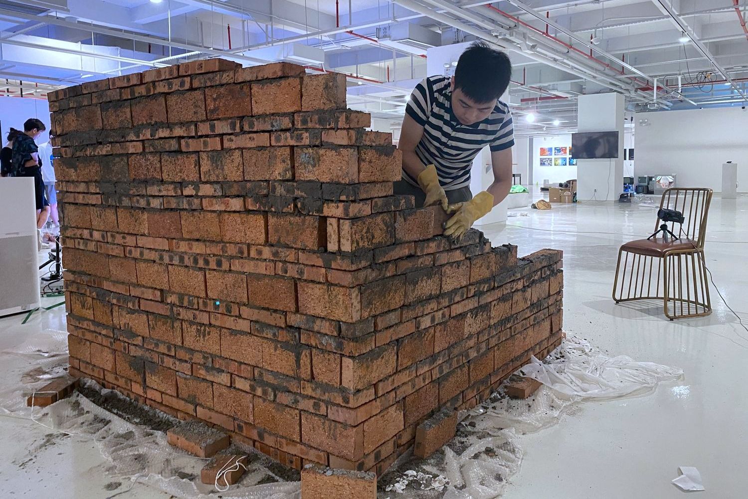 In 2021, Guo Dingfeng spent three and a half days building a cube out of bricks in the art museum as part of the  “Life on the Scaffolding” project