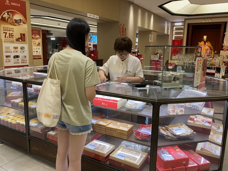 A young female Chinese shopper purchasing TCM at a shop counter