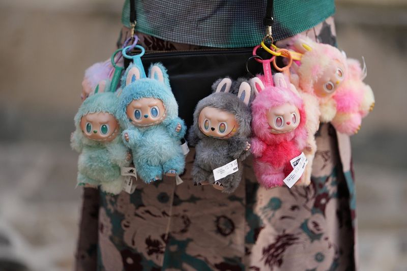 Multiple colorful Labubu dolls hanging from a fan's purse