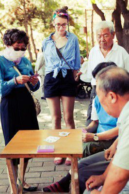 A girl observes a card game among the local Chinese.