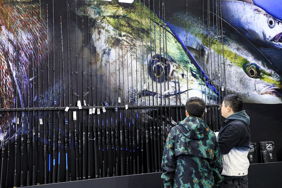 Chinese men examine different fishing rods at the Luya fishing exhibition in Shanghai