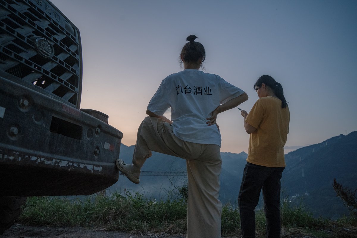 Two distillery workers stand idly after work, wondering how to pass the time from dusk to dawn