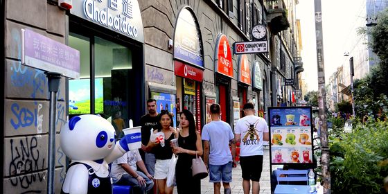 Pedestrians walking by Chinese milk tea shop Milan Chinatown