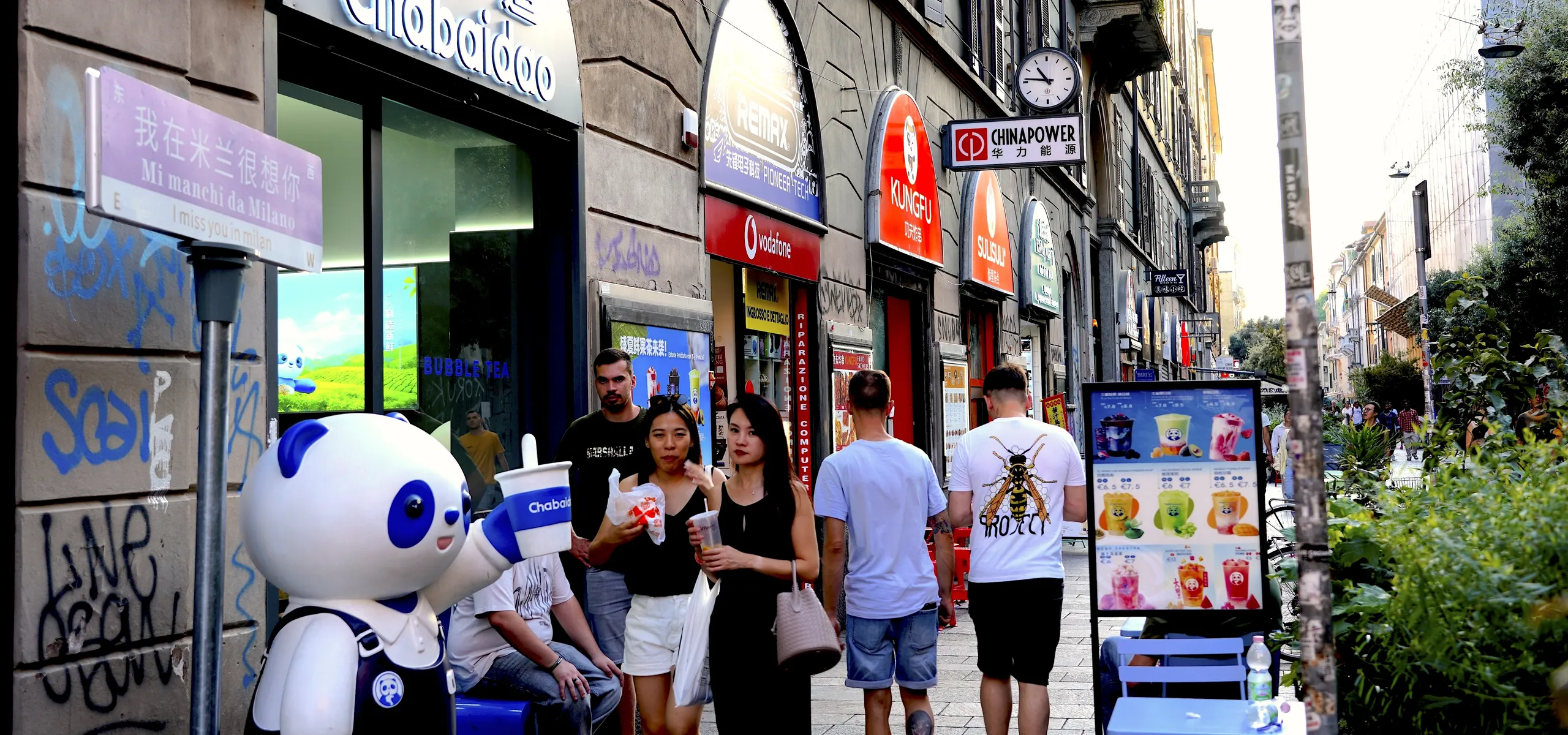 Pedestrians walking by Chinese milk tea shop Milan Chinatown