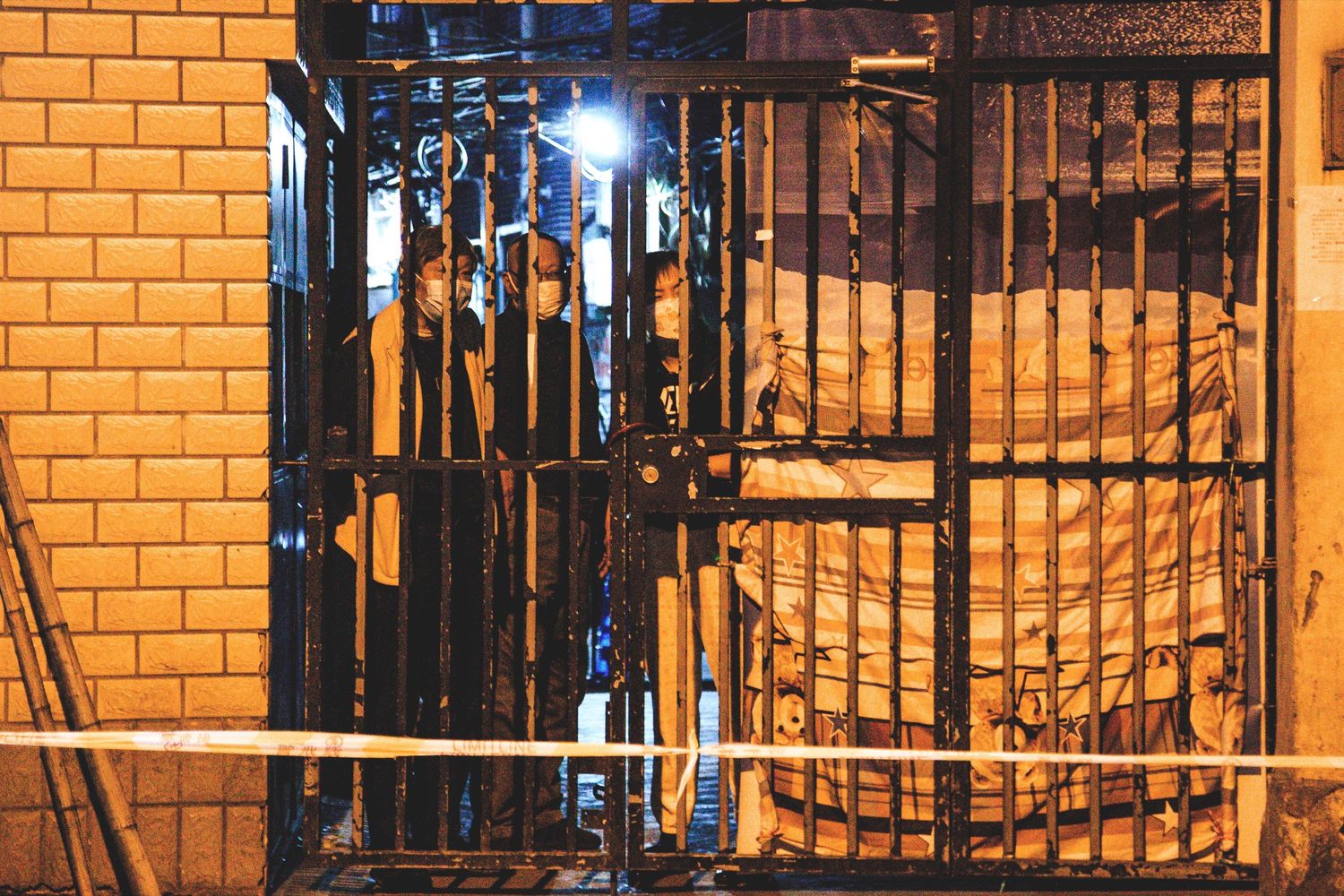 Residents peer out through their locked compound gate.