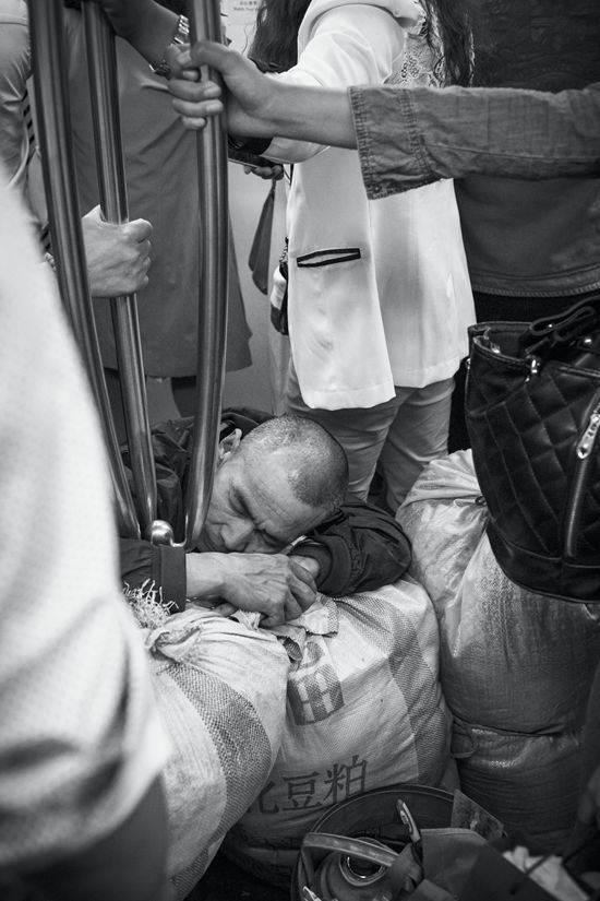 A Chinese man napping after a hard day&#x27;s work while squatting on a bus. 