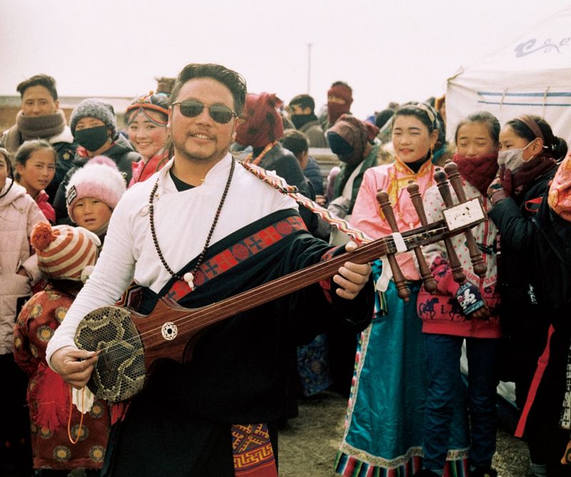 A man plays the dramyin at the Tibetan New Year festivities